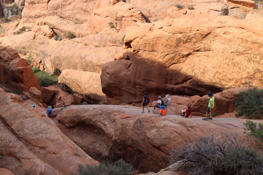Walking down the fin on Devils Garden Trail at Arches National Park, Utah